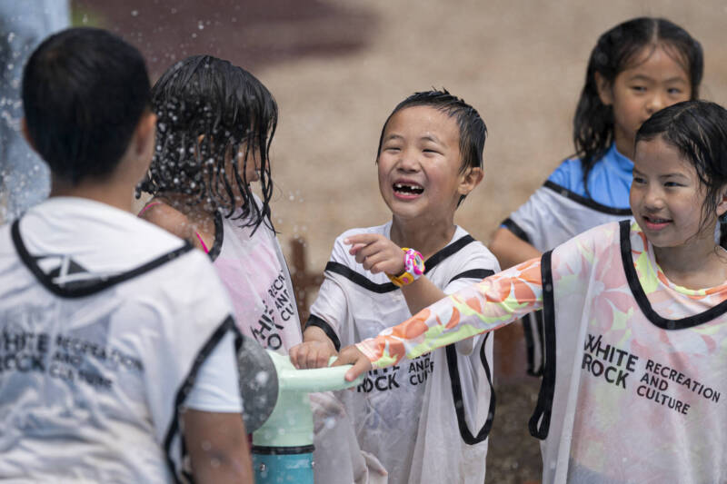 Kids playing with a Splash Blaster water feature from Waterplay at a community splash pad