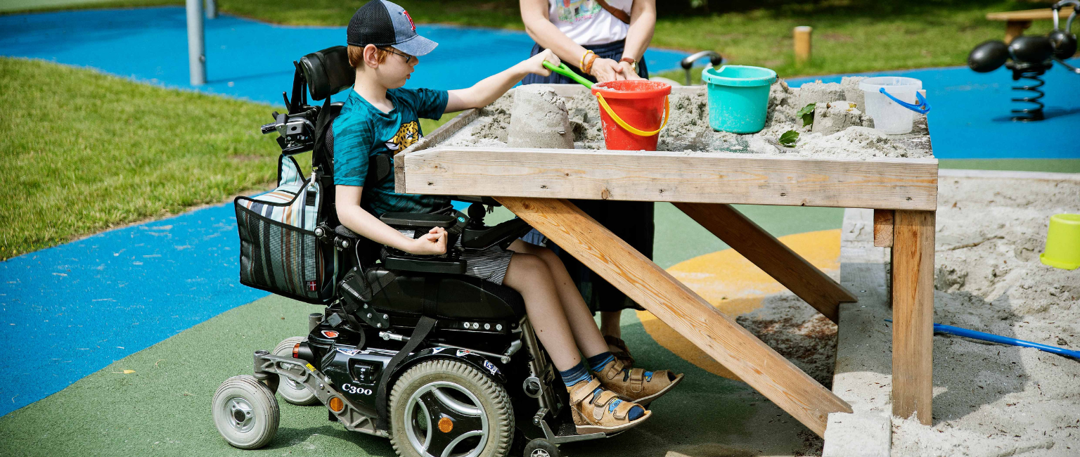 PW Blog Graphics (2) Young boy in wheelchair playing on playground with pour in place rubber playground surfacing