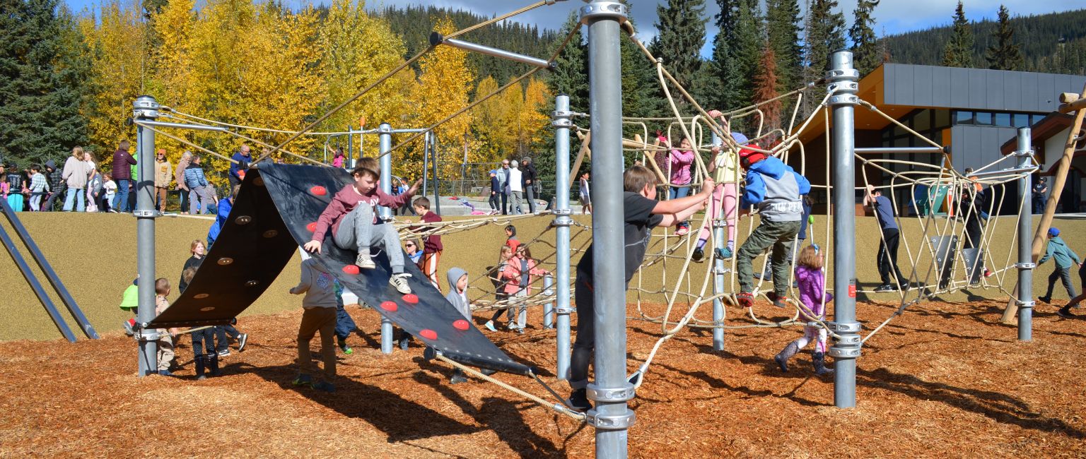 Kids playing on a playground climbing structure at Sun Peaks, BC