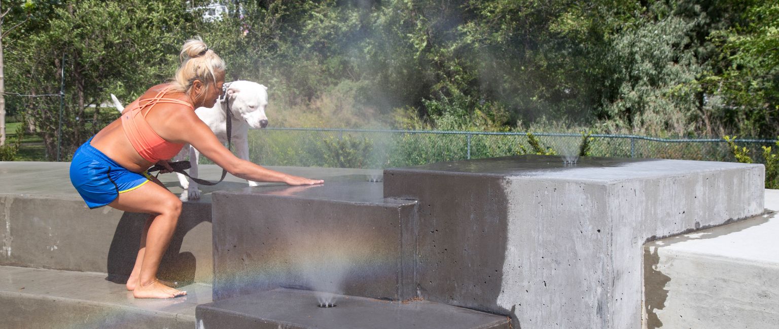 A woman and her dog test out the misting features at Skaha Lake Splash Pad in Penticton, BC