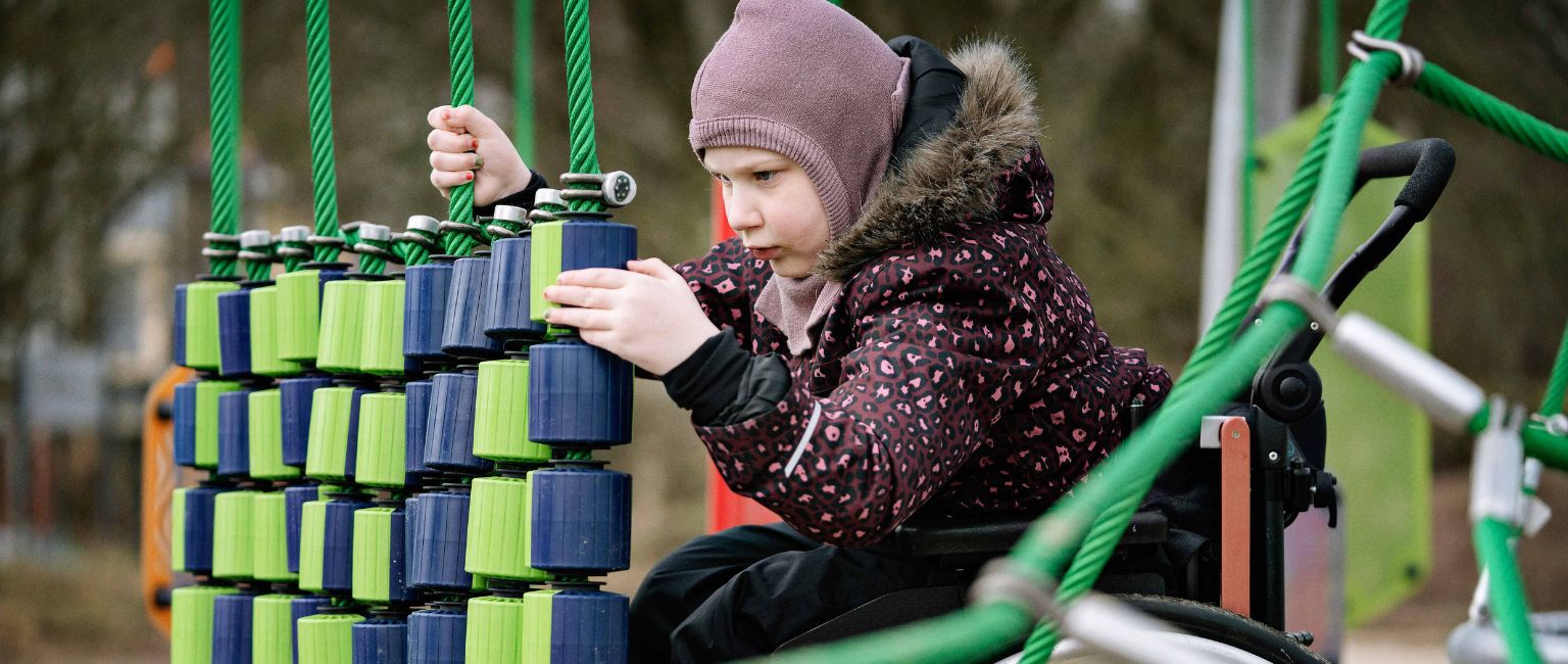 Young girl playing with sensory playground equipment in an inclusively designed play space