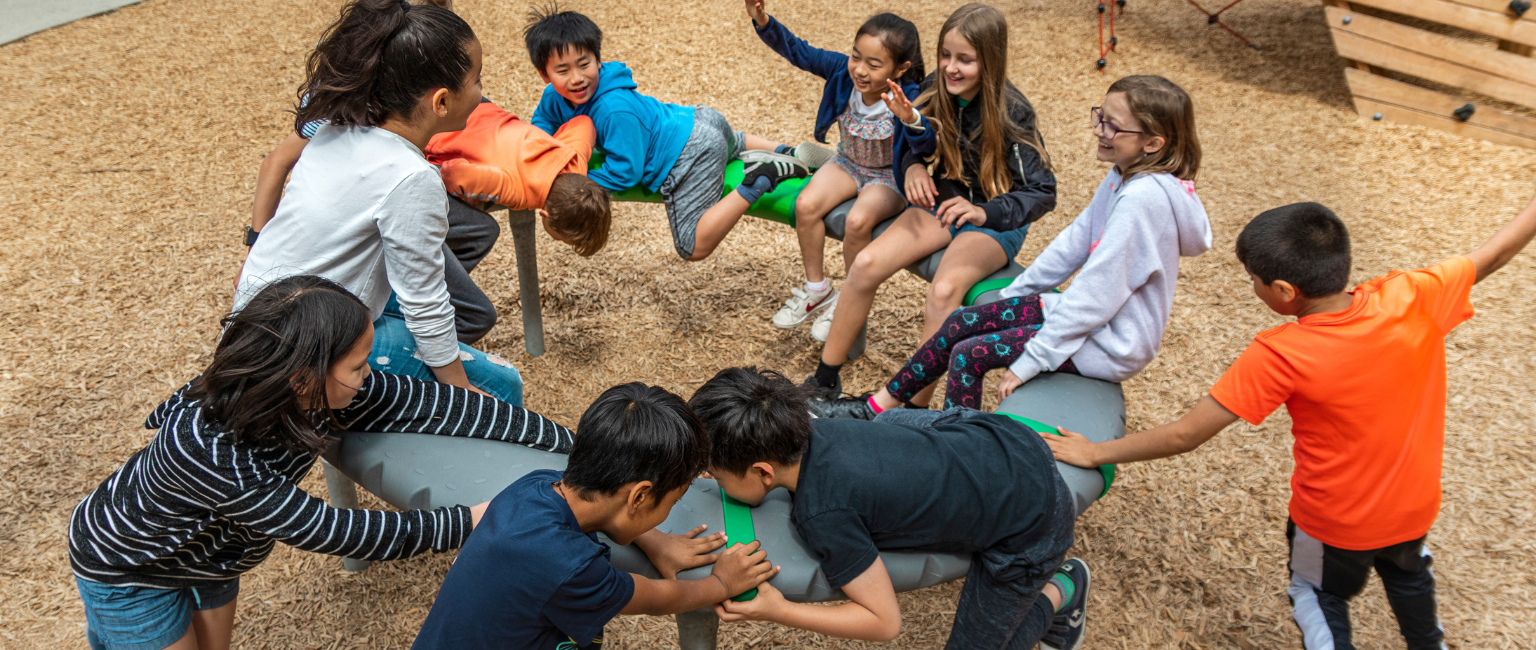 Kids playing on a KOMPAN supernova structure in a community playground.