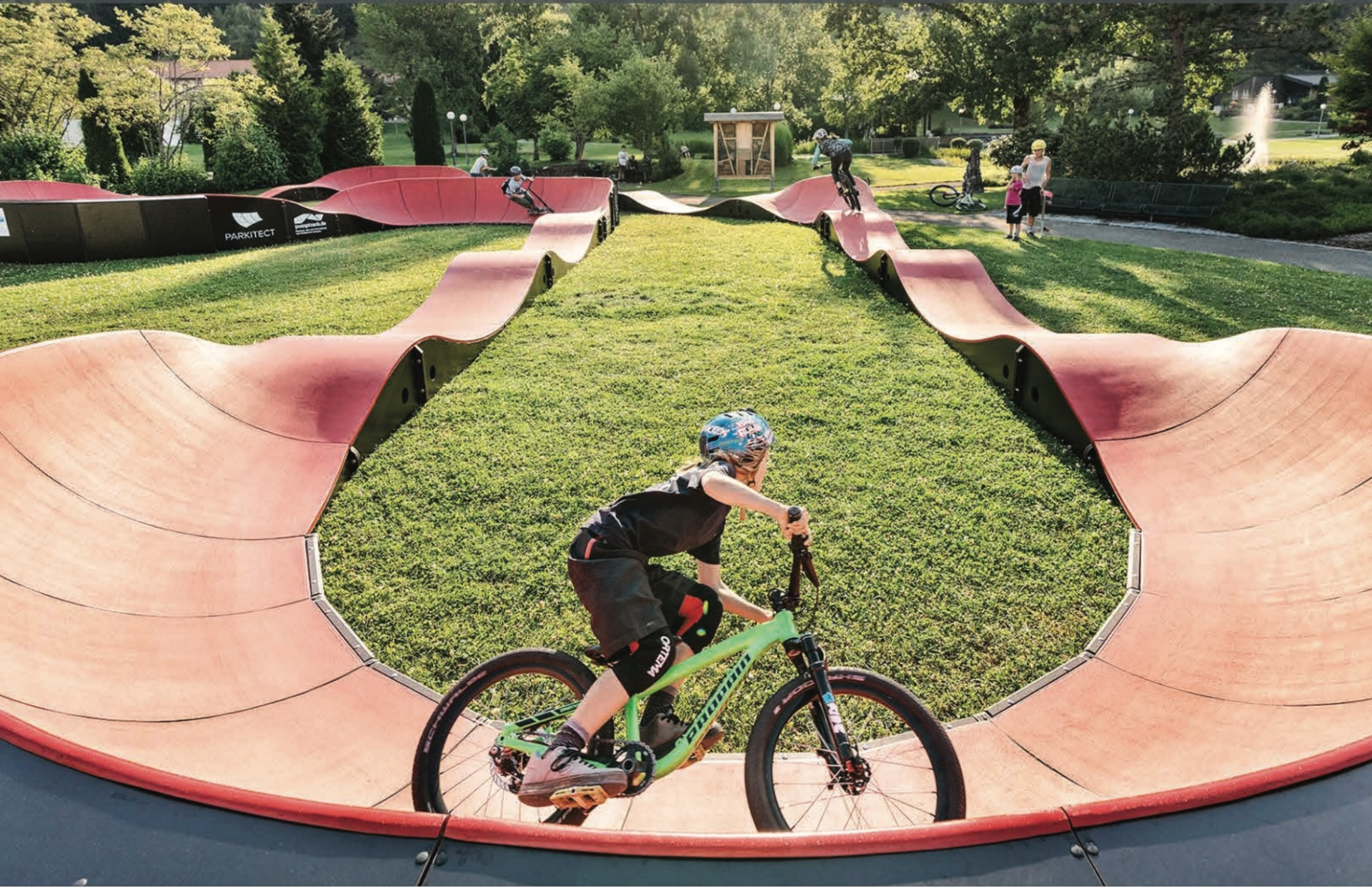 Young boy riding bike on a Parkitect Classic pump track